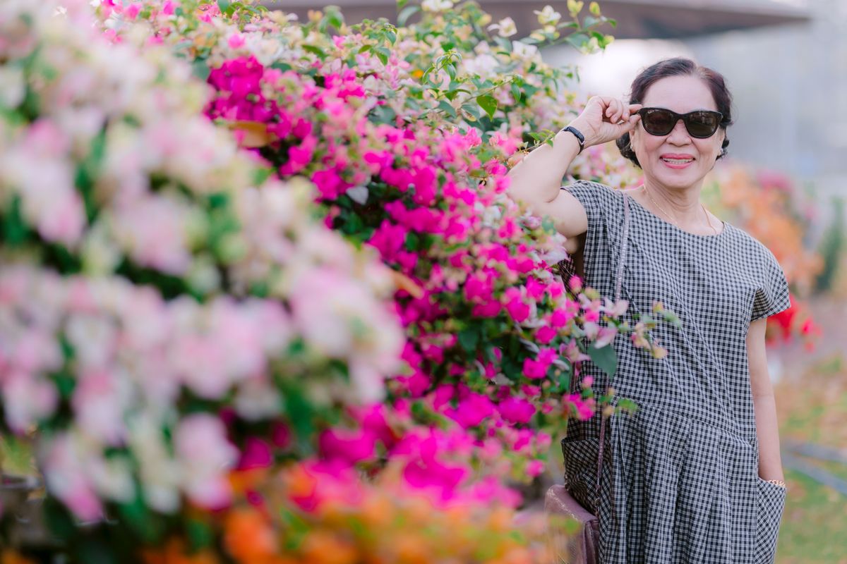 A smiling older patient enjoying a sunny day in a flower garden